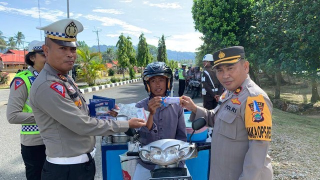 Wakapolres Kaimana Kompol Mapparenta, S. Sos (kanan) bersama Kasat Lantas Polres Kaimana, AKP Yosias S Tatuhey, S. Sos saat menyerahkan coklat kepada pengendara roda dua