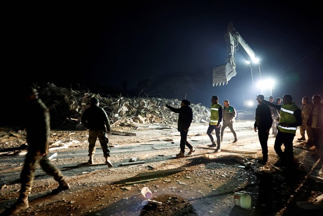 Orang-orang berjalan di luar gedung yang runtuh setelah gempa bumi di Antakya di provinsi Hatay, Turki, Senin (20/2/2023). Foto: Clodagh Kilcoyne/REUTERS