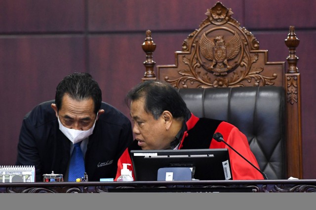 Hakim Konstitusi Arief Hidayat (kanan) berbicara dengan panitera sebelum memimpin Sidang Uji Materi Undang-undang Nomor 7 Tahun 2017 tentang Pemilihan Umum di Mahkamah Konstitusi (MK), Jakarta, Selasa (21/2/2023). Foto: Aditya Pradana Putra/Antara Foto