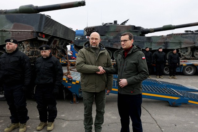 Perdana Menteri Ukraina Denys Shmyhal dan Perdana Menteri Polandia Mateusz Morawiecki berjabat tangan di samping tank Leopard 2 pertama yang dikirim dari Polandia di lokasi yang dirahasiakan, di Ukraina. Foto: Krystian Maj/Kanselir Perdana Menteri Polandia/via REUTERS