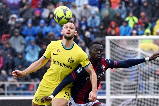 Pemain Inter Milan Stefan de Vrij berebut bola dengan pemain Bologna Musa Barrow pada pertandingan lanjutan Liga Italia di Stadio Renato Dall'Ara, Bologna, Italia, Minggu (26/2/2023).  Foto: Alberto Lingria/REUTERS