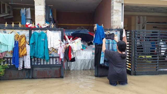 Warga menjemur pakaian di tengah banjir. Dok: kumparan.