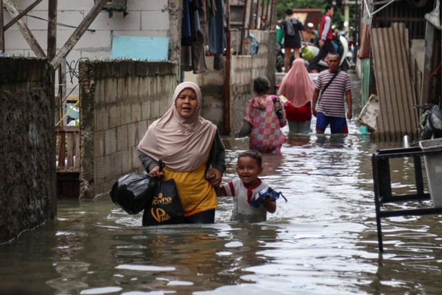 Sejumlah warga melintasi genangan banjir di Rawa Buaya, Cengkareng, Jakarta Barat, Senin (27/2/2023).  Foto: Prabanndaru Wahyuaji/ANTARA FOTO