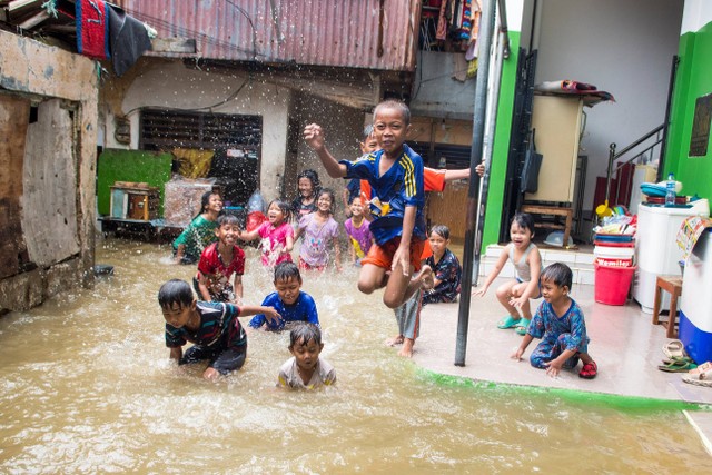 Sejumlah bocah bermain saat banjir merendam kawasan pemukiman penduduk, Kebon Pala, Jakarta, Senin (27/2/2023).  Foto: Muhammad Adimaja/ANTARA FOTO