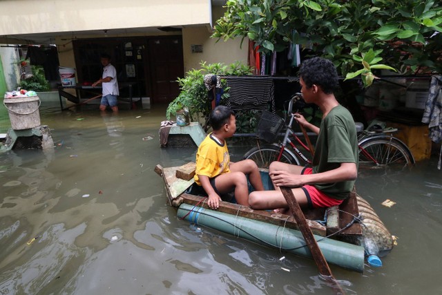Sejumlah warga melintasi genangan banjir di Rawa Buaya, Cengkareng, Jakarta Barat, Senin (27/2/2023). Foto: Prabanndaru Wahyuaji/ANTARA FOTO