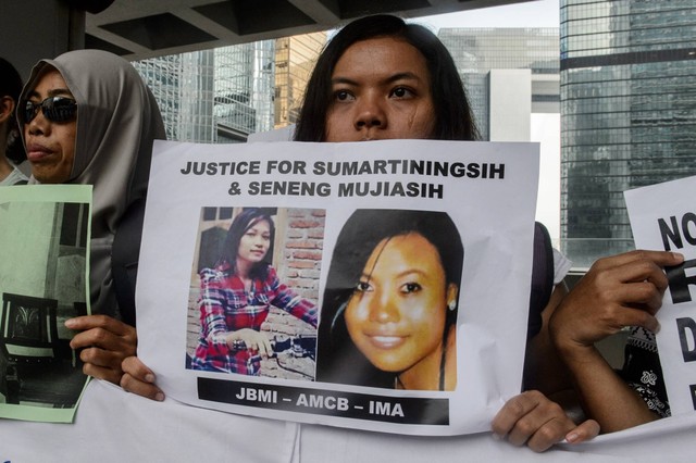 Seorang buruh migran mengangkat secarik kertas yang memperlihatkan foto Sumarti Ningsih (kiri) dan Seneng Mujiasih (kanan), saat protes di luar Pengadilan Tinggi di Hong Kong pada 8 November 2016. Foto: Anthony Wallace/AFP
