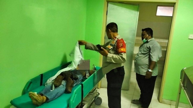 Polisi saat memeriksa kondisi jenazah pria yang ditikam OTD saat minum tuak di Palembang. (ist)