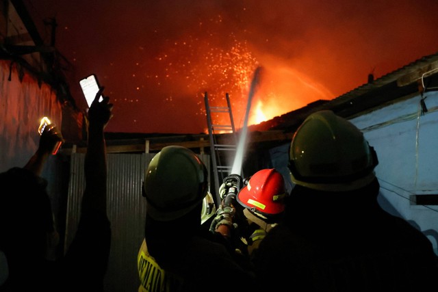 Petugas berusaha memadamkan api kebakaran Depo Pertamina Plumpang, Jakarta Utara, Jumat (3/3/2023) dari arah pemukiman warga. Foto: Willy Kurniawan/REUTERS