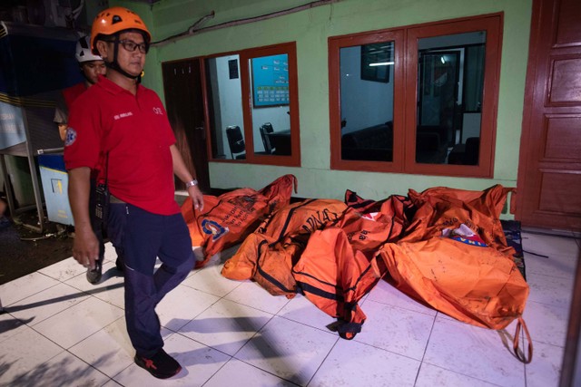 Seorang petugas melintasi kantong berisi jenazah korban kebakaran Pipa Pertamina Plumpang di Jakarta, Jumat (3/3/2023). Foto: ANTARA FOTO/Wahyu Putro A