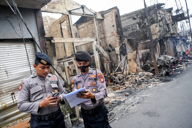 Anggota Polri mendata dampak dari permukiman yang hangus terbakar pascakebakaran Depo Pertamina Plumpang di Jalan Koramil, Rawa Badak Selatan, Koja, Jakarta, Sabtu (4/3/2023). Foto: M Risyal Hidayat/ANTARA FOTO