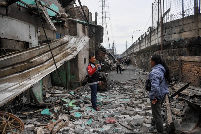 Warga berfoto tak jauh dari permukiman yang hangus terbakar dan hancur pascakebakaran Depo Pertamina Plumpang di Jalan Koramil, Rawa Badak Selatan, Koja, Jakarta, Sabtu (4/3/2023). Foto: M Risyal Hidayat/ANTARA FOTO