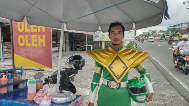 Seorang penjual cilok bernama Juwanso (40) di Kabupaten Sleman mengenakan kostum Power Rangers hijau saat berdagang, Sabtu (4/3). Foto: Arfiansyah Panji Purnandaru/kumparan