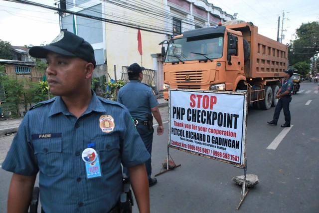 Polisi menjaga pos pemeriksaan antara perbatasan Kota Tanjay dan kota Pamplona di Provinsi Negros Oriental Filipina pada 4 Maret 2023. Foto: FERDINAND EDRALIN/AFP
