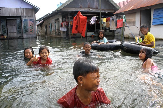 Sejumlah anak-anak bermain air di depan rumahnya yang terendam banjir di Desa Sungai Rangas Ulu, Kabupaten Banjar, Kalimantan Selatan, Minggu (5/3/2023). Foto: Bayu Pratama S/ANTARA FOTO