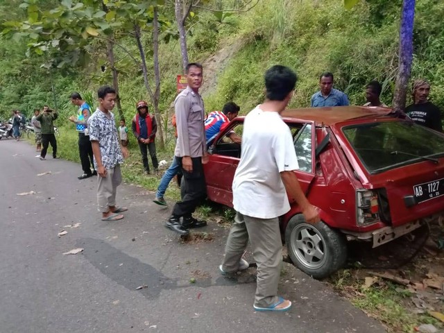 Warga mengevakuasi mobil tua yang menabrak pohon jati usai alami rem blong di Tanjakan Bibis Kulon Progo. Foto: istimewa