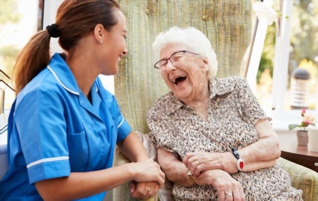 Wanita Senior Duduk Di Kursi Dan Berbicara Dengan Perawat Dalam Pensiun. Shutterstock