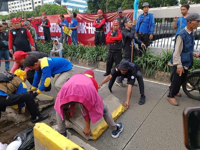 Massa aksi buruh dan petani yang berdemo di depan Gedung DPR, Jakarta menutup jalur Trans Jakarta, Selasa (14/3/2023). Foto: Zamachsyari/kumparan