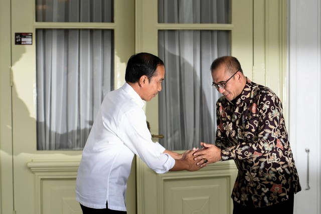 Presiden Joko Widodo (kiri) menyalami Ketua KPU Hasyim Asy'ari usai pencocokan dan penelitian (Coklit) data pemilih untuk Pemilu 2024 di Istana Merdeka, Jakarta, Selasa (14/2/2023). Foto: Hafidz Mubarak A/Antara Foto