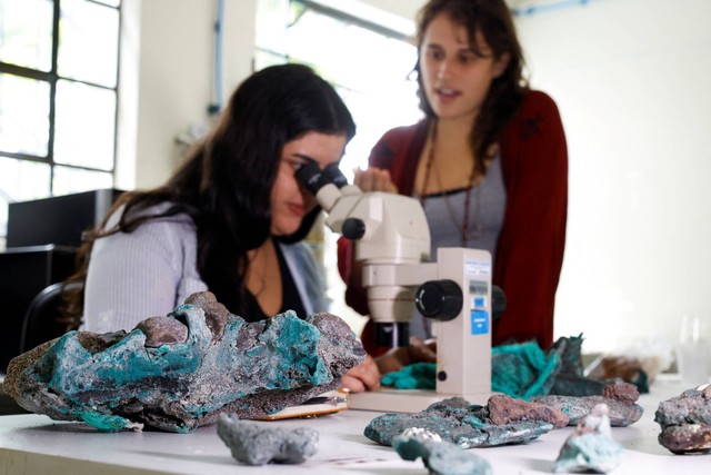 Peneliti Fernanda Avelar Santos melihat melalui mikroskop pada "batuan plastik" yang ditemukan di Pulau Trindade di negara bagian Espirito Santo, di laboratorium Universitas Federal Parana, di negara bagian Curitiba Parana, Brasil 7 Maret 2023. Foto: Rodolfo Buhrer/Reuters