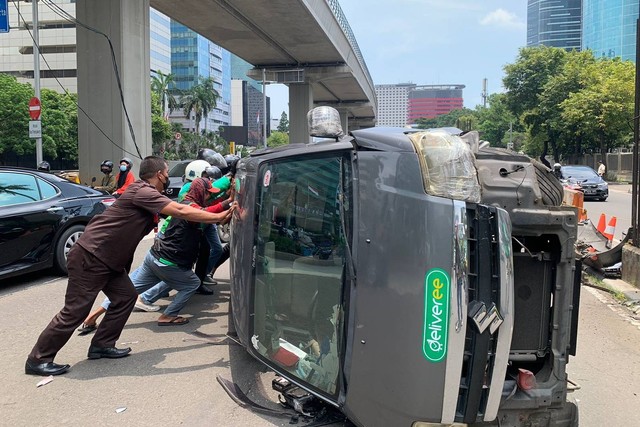Ojol dan warga menggeser mobil terbalik di depan gedung KPK, Jalan Rasuna Said, Jakarta, Jumat (17/3/2023). Foto: Luthfi Humam/kumparan