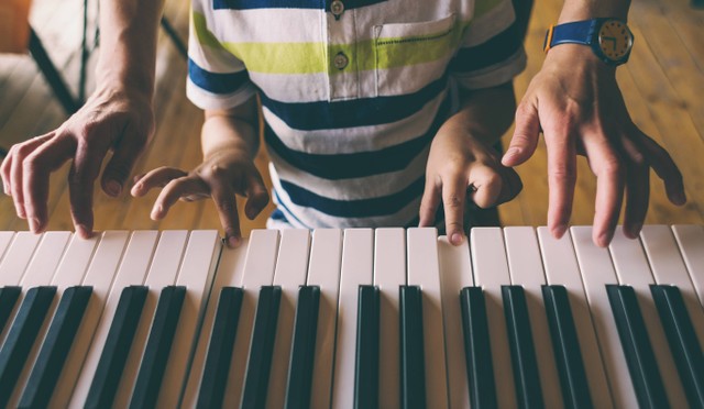 Seorang wanita mengajari putranya bermain piano. Foto: zhukovvvlad/Shutterstock.