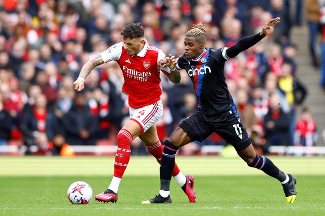 Pemain Arsenal Ben White berebut bola dengan pemain Crystal Palace Wilfried Zaha pada pertandingan lanjutan Liga Inggris di Stadion Emirates, London, Inggris, Minggu (19/3/2023).  Foto: Peter Cziborra/REUTERS