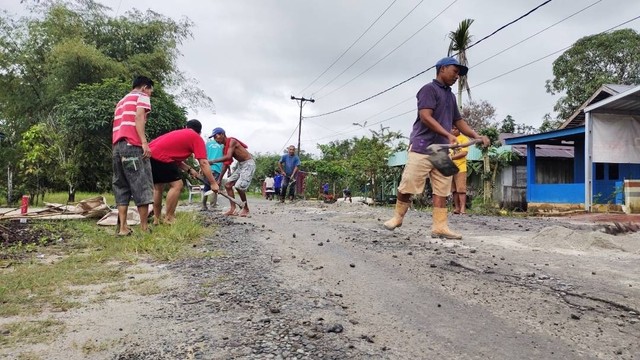 Warga secara swadaya bergotong royong memperbaiki jalan berlubang. Pasalnya, kerusakan yang terjadi kerap membuat pengendara mengalami kecelakaan. Foto: Lukman Hakim/InfoPBUN