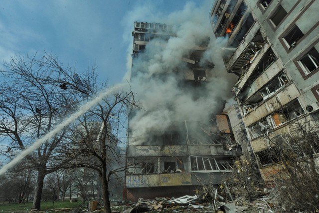 Petugas pemadam kebakaran berusaha memadamkan kebakaran bangunan tempat tinggal yang rusak akibat serangan misil Rusia di Zaporizhzhia, Ukraina, Rabu (22/3/2023). Foto: Sergiy Chalyi/REUTERS
