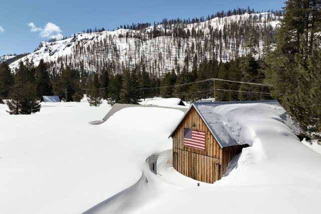 Sebuah rumah yang diselimuti salju terlihat di area dekat Danau Tahoe yang mengalami rekor tingkat salju musim dingin ini di Christmas Valley, California, AS, Jumat (24/3/2023). Foto: Fred Greaves/REUTERS