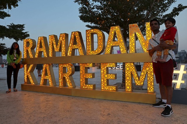 Sejumlah masyarakat berjalan melewati dekorasi selama bulan suci Ramadhan di Al-Seef di Dubai pada Minggu (26/3/2023). Foto: Giuseppe Cacace/AFP