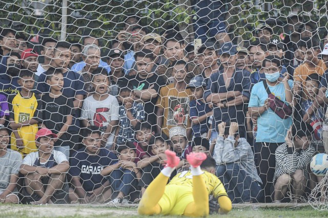 Penonton menyaksikan penjaga gawang yang gagal menghalau bola dalam turnamen Kades Cup 1 di lapangan Bonek Arena Tangerang, Banten. Foto: M Risyal Hidayat/ANTARA FOTO