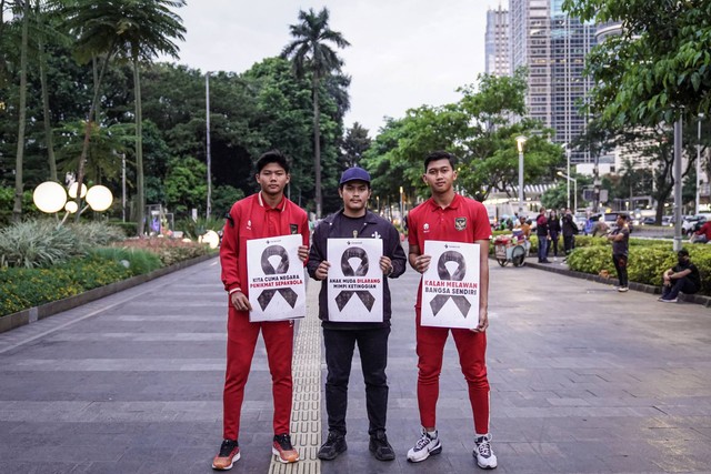 Ketua komunitas CentennialZ Dinno Ardiansyah (tengah) bersama Pemain Timnas U-20 Arkhan Kaka (kiri) dan Aditya Arya Nugraha (kanan) memegang poster saat mengikuti "Aksi Duka 1 Juta Pita Hitam" di kawasan Senayan, Jakarta, Jumat (31/3/2023). Foto: Dhemas Reviyanto/ANTARA FOTO