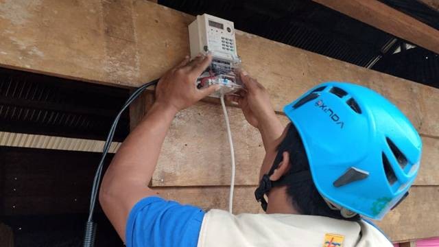 Petugas PLN memasang meter listrik di rumah warga kurang mampu.