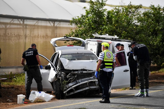 Petugas medis dan polisi Israel memeriksa mobil yang rusak di lokasi serangan penembakan, di Lembah Yordan di Tepi Barat yang diduduki Israel, Jumat (7/4/2023). Foto: Gil Eliyahu/REUTERS