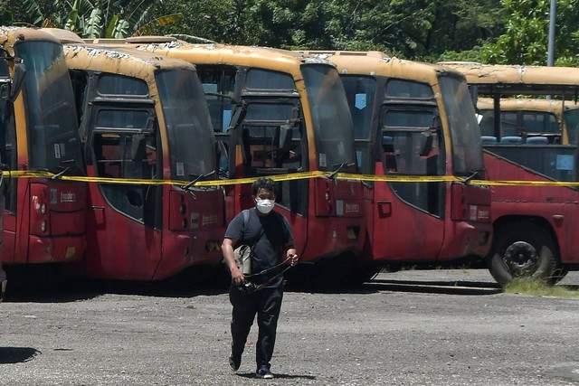 Jurnalis melintas disamping bus Transjakarta yang parkir di area Terminal Terpadu Pulo Gebang, Jakarta Timur, Rabu (12/4/2023). Foto: Fakhri Hermansyah/ANTARA FOTO