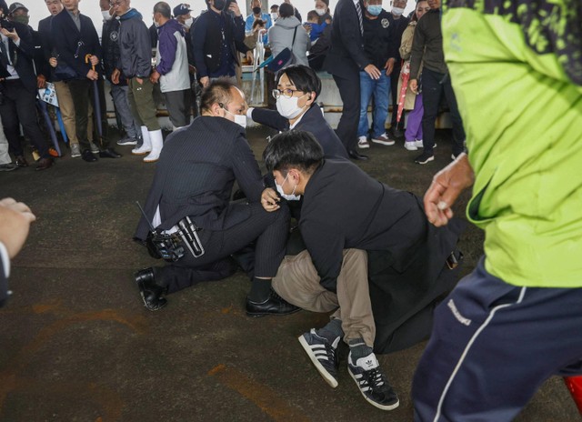 Petugas polisi menangkap pria sebagai tersangka yang melemparkan benda mirip pipa ke Perdana Menteri Jepang Fumio Kishida saat pidato di Wakayama, Prefektur Wakayama, Jepang barat daya, Sabtu (15/4/2023). Foto: Kyodo melalui REUTERS