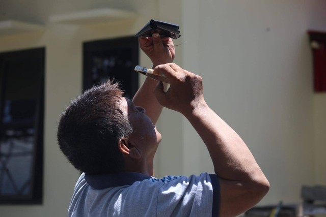 Seorang warga di Manado sedang melihat Gerhana Matahari Hibrida dengan peralatan seadanya.