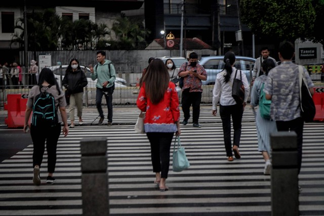 Pekerja melintas di pelican crossing di kawasan perkantoran Sudirman, Jakarta, Rabu (26/4/2023). Foto: Jamal Ramadhan/kumparan