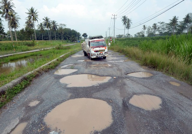 Pengendara mobil melintas di antara jalan berlubang yang tergenang air di jalan terusan Ryacudu Jati Agung, Lampung Selatan Lampung, Rabu (3/5/2023). Foto: Ardiansyah/ANTARA FOTO