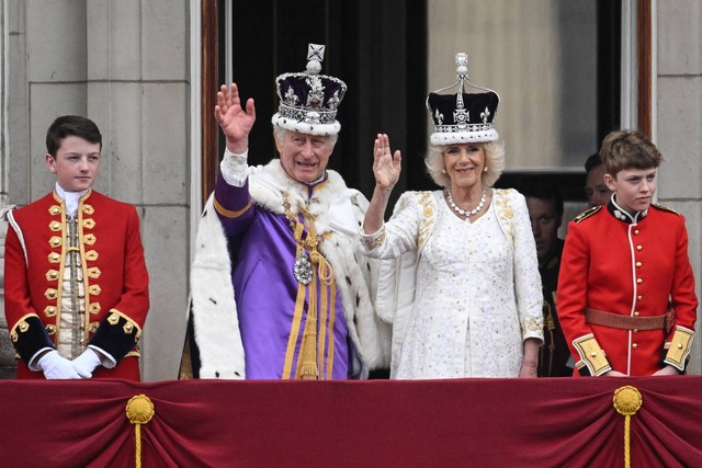 Raja Charles III mengenakan Mahkota negara Kekaisaran, dan Ratu Inggris Camilla mengenakan versi modifikasi dari gelombang Mahkota Ratu Mary melambaikan tangan di balkon Istana Buckingham, London, Sabtu (6/5/2023). Foto: Marco Bertorello/AFP