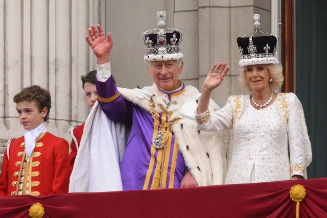 Raja Charles III mengenakan Mahkota negara Kekaisaran, dan Ratu Inggris Camilla mengenakan versi modifikasi dari gelombang Mahkota Ratu Mary melambaikan tangan di balkon Istana Buckingham, London, Sabtu (6/5/2023). Foto: Daniel Leal/AFP