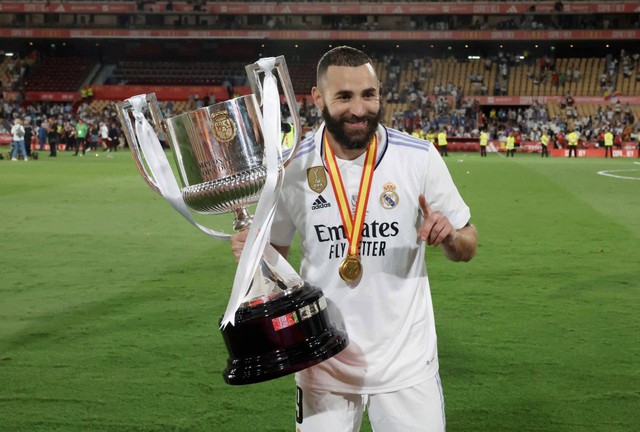 Karim Benzema dari Real Madrid mengangkat trofi setelah memenangkan pertandingan final Copa del Rey di Estadio de La Cartuja, Seville, Spanyol. Foto: Jon Nazca/Reuters