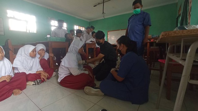 Petugas puskesmas tengah memeriksa kondisi para siswa MIS Ma'arif Giriloyo II Bantul. Foto: Dok. Polres Bantul