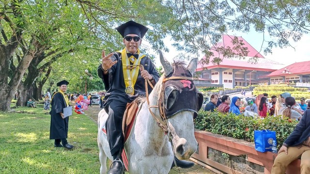 Seorang wisudawan program pascasarjana UGM Endra Harsaya (60) atau Hendro Plered naik kuda keliling Grha Sabha Pramana (GSP) UGM, Rabu (10/5). Foto: Arfiansyah Panji/kumparan