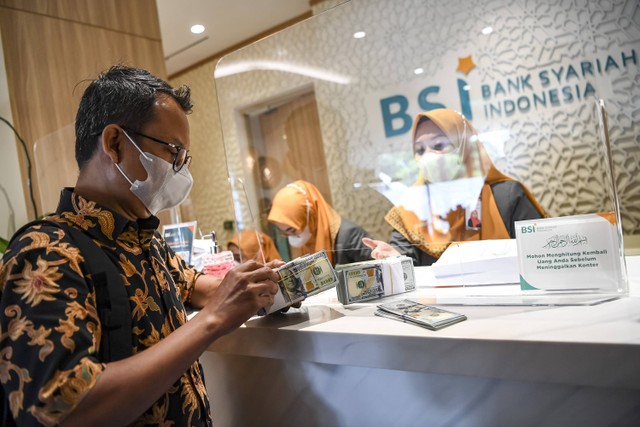 Nasabah membawa uang dolar AS usai bertransaksi di Kantor Cabang BSI Jakarta Thamrin, Jakarta, Kamis (11/5/2023). Foto: ANTARA FOTO/M Risyal Hidayat