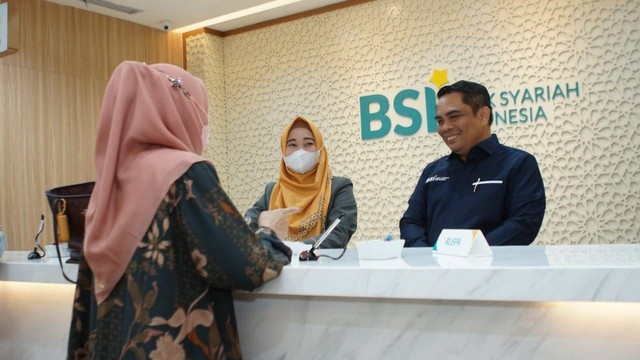 Direktur Sales & Distribution BSI Anton Sukarna (kanan) dan petugas teller BSI saat melayani pelunasan biaya Haji nasabah Bank BSI seiring dengan pulihnya layanan cabang dan ATM Bank BSI. Foto: BSI
