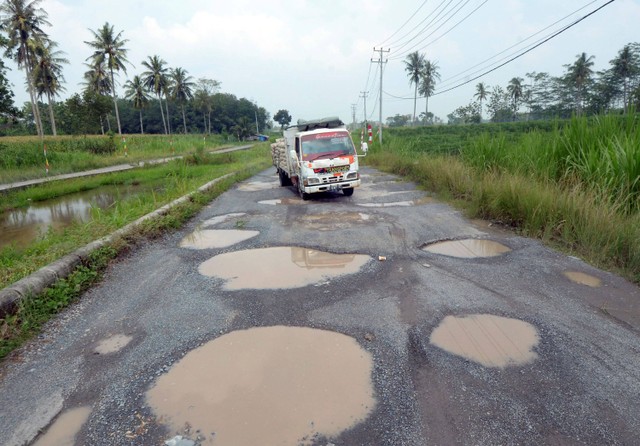 Pengendara mobil melintas di antara jalan berlubang yang tergenang air di jalan terusan Ryacudu Jati Agung, Lampung Selatan Lampung, Rabu (3/5/2023). Foto: Ardiansyah/Antara Foto