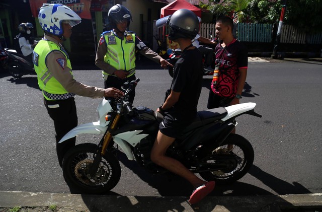 Anggota Kepolisian Korps Lalu Lintas melakukan penindakan tilang manual kepada pengendara sepeda motor di Kota Ternate, Maluku Utara, Rabu (17/5/2023). Foto: ANTARA FOTO/Andri Saputra