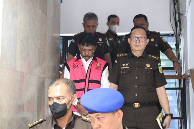 Menteri Komunikasi dan Informatika Johnny G Plate (tengah) mengenakan baju tahanan berjalan usai menjalani pemeriksaan di Kejaksaan Agung (Kejagung), Jakarta, Rabu (17/5/2023). Foto: Kejagung