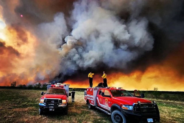 Petugas pemadam kebakaran berdiri di atas truk Kamloops Fire Rescue saat kebakaran hutan di dekat Fort St. John, British Columbia, Kanada pada 14 Mei 2023. Foto: Kamloops Fire Rescue/Reuters